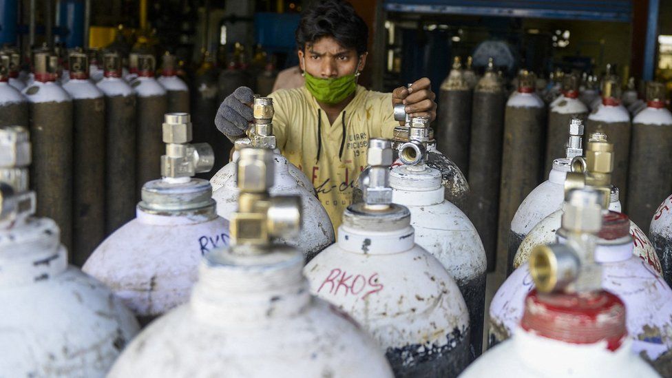 Worker arranges oxygen cylinders for transport to hospital in Hyderabad, India (23 April)