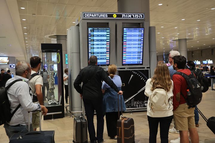 Passengers look at a departure board at Ben Gurion Airport near Tel Aviv, Israel, on October 7, 2023, as flights are canceled because of the Hamas surprise attacks. The conflict sparked major disruption at Tel Aviv airport, with American Airlines, Emirates, Lufthansa and Ryanair among carriers with cancelled flights. (Photo by GIL COHEN-MAGEN / AFP) (Photo by GIL COHEN-MAGEN/AFP via Getty Images)