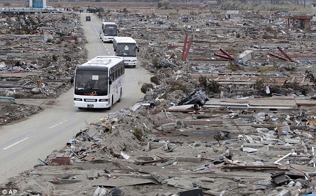 Destruction: A bus takes people past a flattened suburb in Miyagi Prefecture two weeks after the disaster in March 2011