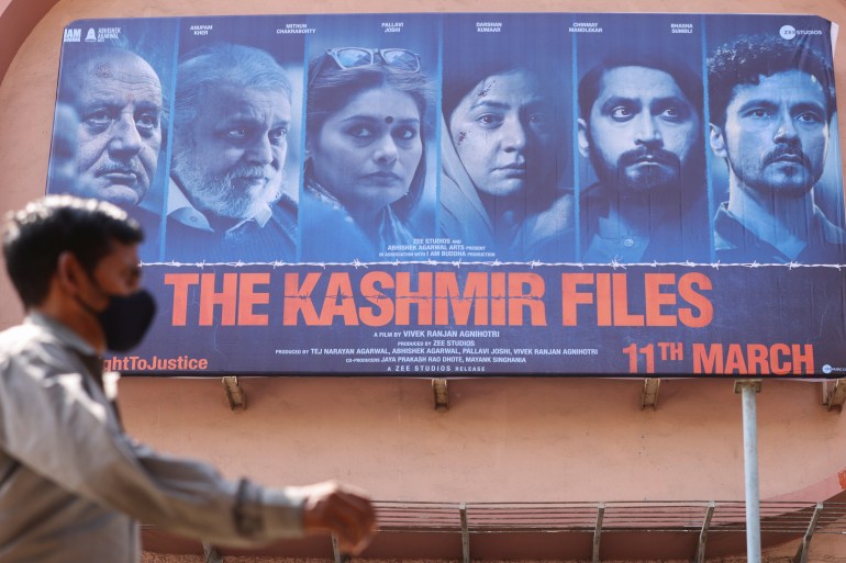 A man walks past a poster of Bollywood movie The Kashmir Files outside a cinema in Mumbai, India, March 16, 2022.