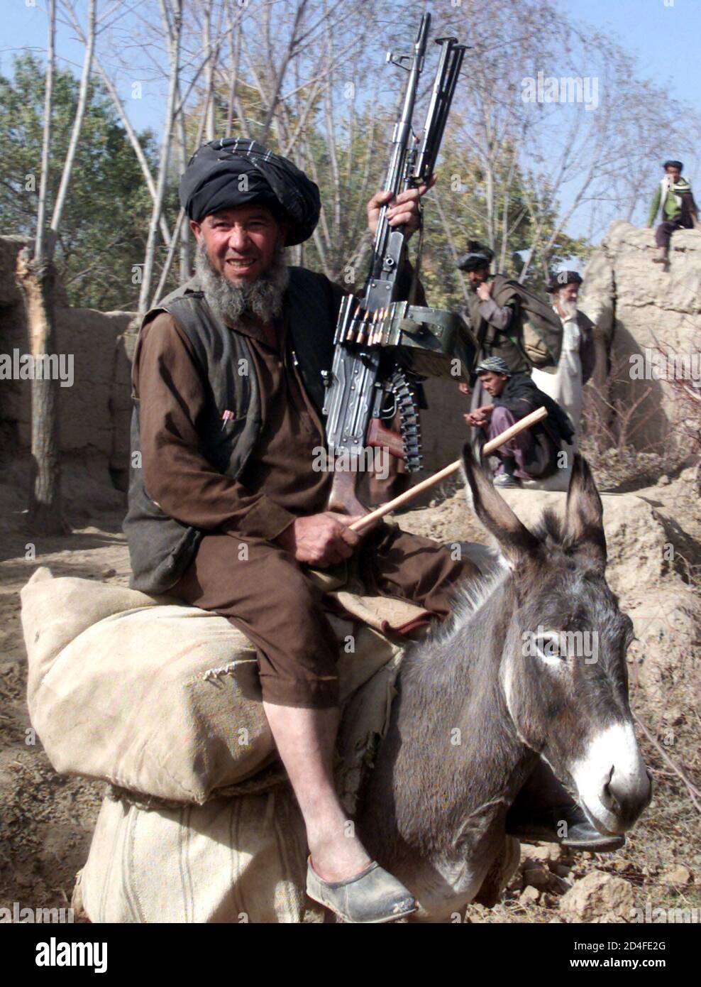 an-afghan-villager-rides-a-donkey-with-machine-gun-in-his-hand-on-the-road-to-talukan-in-takhar-province-northern-afghanistan-november-14-2001-the-northern-alliances-seizure-of-kabul-and-the-domino-like-fall-of-defection-of-towns-and-provinces-has-reduced-the-talibans-control-from-90-percent-of-afghanistan-to-20-percent-in-just-five-days-2D4FE2G.jpg