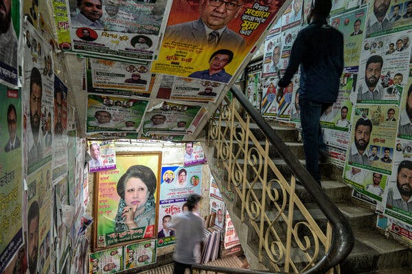 One person walks up steps in a building, while another walks down. All the walls are covered in political posters.