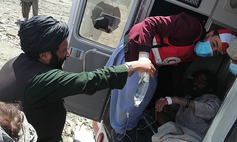 This photograph taken on June 22, 2022 and received as a courtesy of the Afghan government-run *Bakhtar News Agency* shows a member of the Afghan Red Crescent Society giving medical treatment to a victim following an earthquake in Afghanistan's Gayan district, Paktika province. — AFP