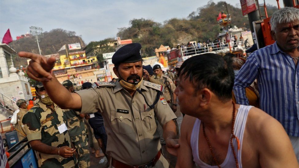 A police officer asks a devotee to leave after a dip
