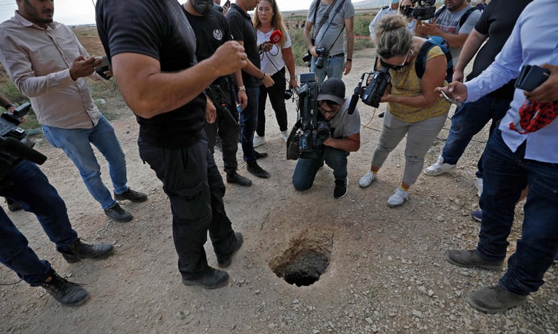 Police and journalists gather around a hole used by six Palestinian prisoners to escape from the Gilboa Prison after they dug a tunnel beneath a sink. — AFP
