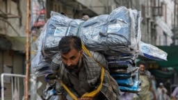 A laborer delivers packs of fabrics to a market during the lockdown in Karachi in May 2020.
