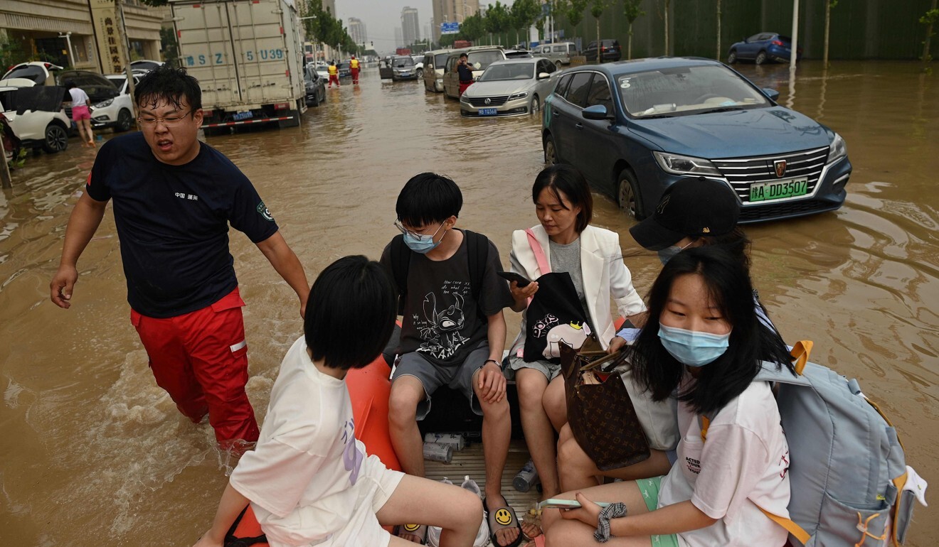 People ride on a rubber boat to cross a flooded street following heavy rain that flooded Henan province last week. Photo: AFP