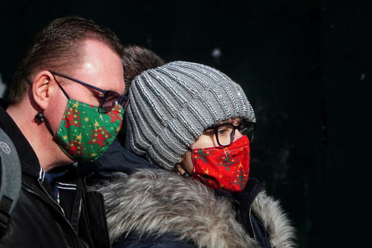 People wear festive masks as they walk though Times Square during the coronavirus disease (COVID-19) pandemic in the Manhattan borough of New York City, New York, U.S., December 15, 2021.  REUTERS/Carlo Allegri