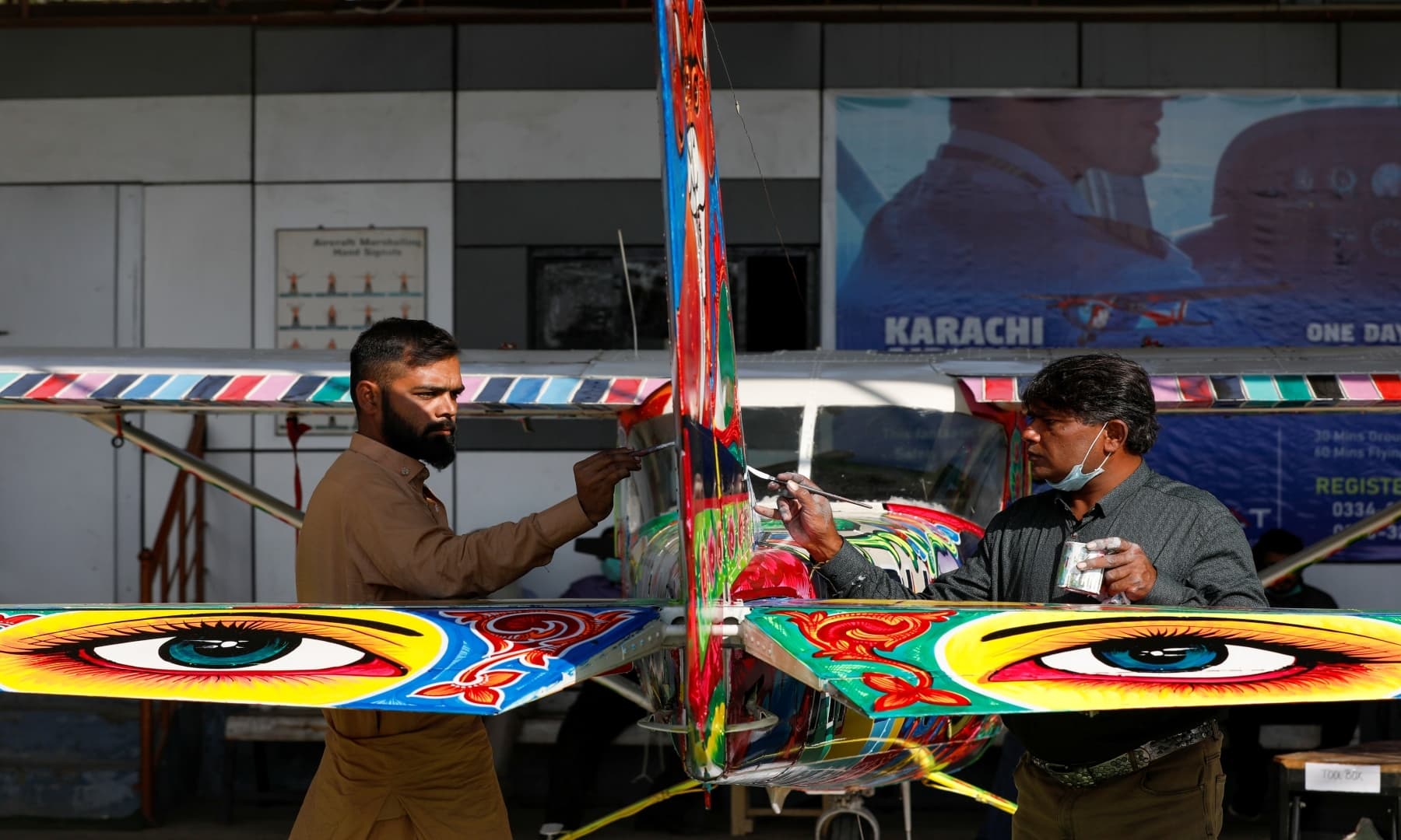 Haider Ali, 40 (R) and his student paint Pakistani truck art on a two-seater Cessna aircraft at general aviation area at Jinnah International Airport, Karachi, Dec 30, 2020. — Reuters