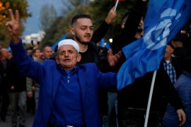A man holds a Democratic Party flag as supporters of the opposition party attend an anti-government protest in front of Prime Minister Edi Rama's office in Tirana, Albania, on November 12, 2022 [Florion Goga/Reuters]