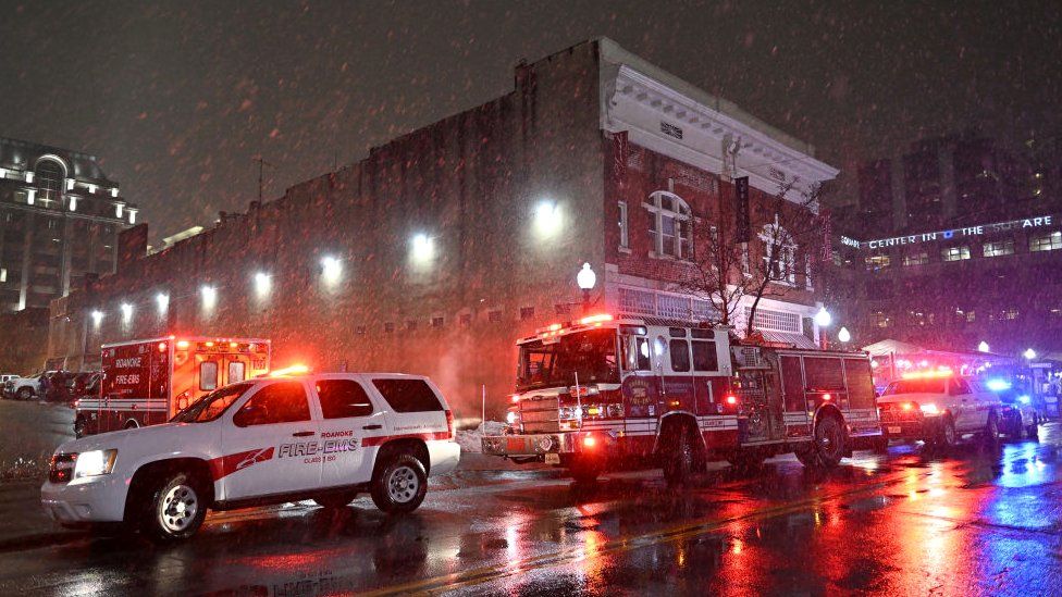 Emergency service vehicles in Charlotte as snow falls in storm