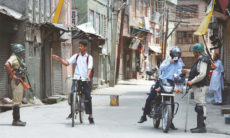 In this file photo, paramilitary personnel stop Kashmiri commuters in Srinagar during a clampdown. — AFP