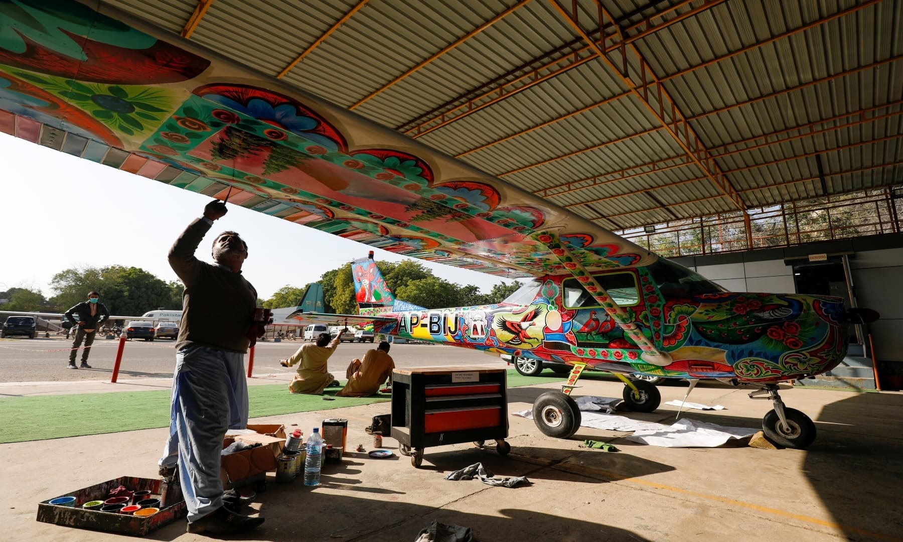 Men paint Pakistani truck art on a two-seater Cessna aircraft at general aviation area at Jinnah International Airport, Karachi, Dec 30, 2020. — Reuters