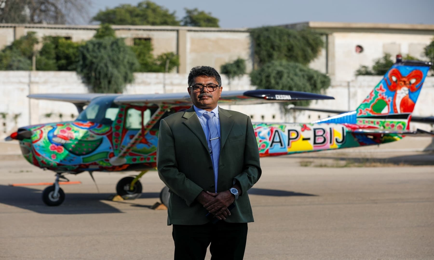 Imran Aslam Khan, Chief Operating Officer of Sky Wings, poses with a two-seater Cessna aircraft painted with Pakistani truck art in the background, at Jinnah International Airport, Karachi, Dec 30, 2020. — Reuters