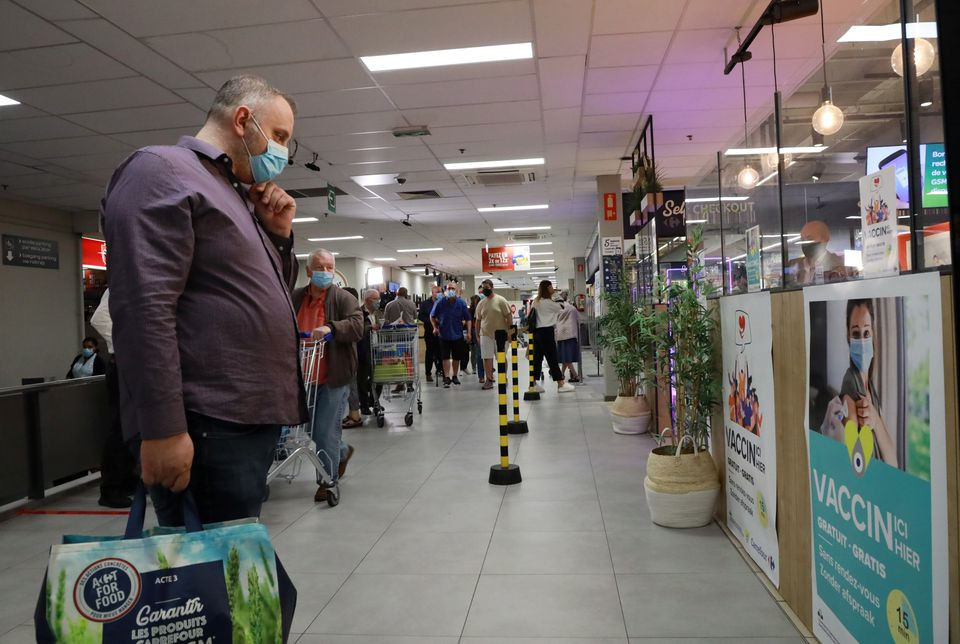 a shopper wearing a protective face masks looks at a poster for a coronavirus disease covid 19 vaccination centre installed inside a supermarket in brussels belgium august 30 2021 photo reuters
