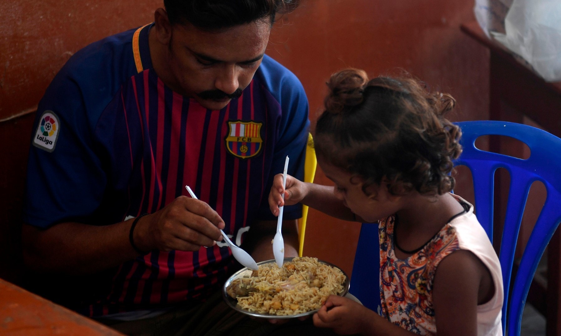 A man eats with his daughter at a restaurant in Karachi on August 10 after the government announced it would be lifting most of the country's remaining coronavirus restrictions. — AFP