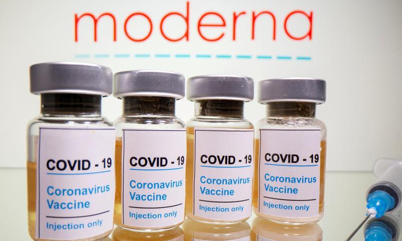 Vials with a sticker reading, Covid-19 / Coronavirus vaccine / Injection only and a medical syringe are seen in front of a displayed Moderna logo. — Reuters/File