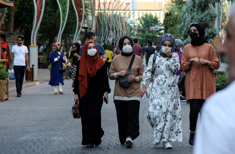  People wearing protective masks walk along a street amid a surge in COVID-19 cases in Diyarbakir, Turkey (credit: SERTAC KAYAR / REUTERS)