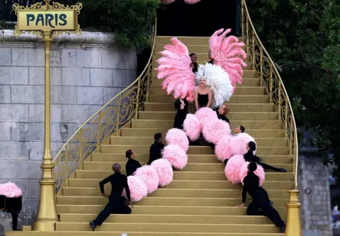 Maja Hitij/Getty Images Lady Gaga performs on a gold staircase with dancers and pink pom poms during the opening ceremony in Paris on 26 July.