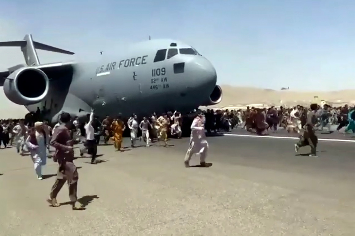 Hundreds of people run alongside a U.S. Air Force C-17 transport plane.