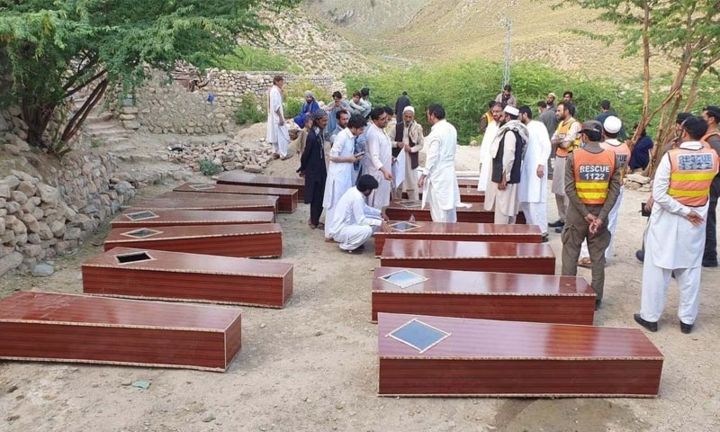 Families of the slain miners and local political leaders stand next to their coffins in Dara Adamkhel on Friday. — Photo by author