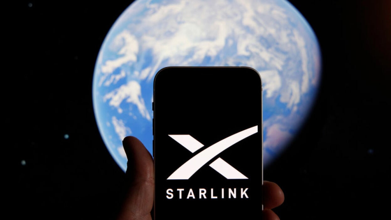 The Starlink logo on a smartphone, in front of an image of the Earth from space.