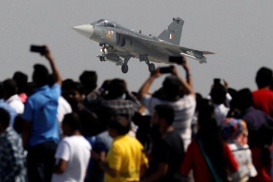 Spectators take pictures as the Indian Air Force (IAF) light combat aircraft 