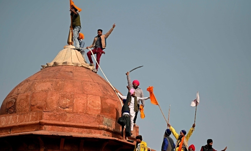 Protesters climb on a dome at the ramparts of the Red Fort during the protest in New Delhi on January 26. — AFP