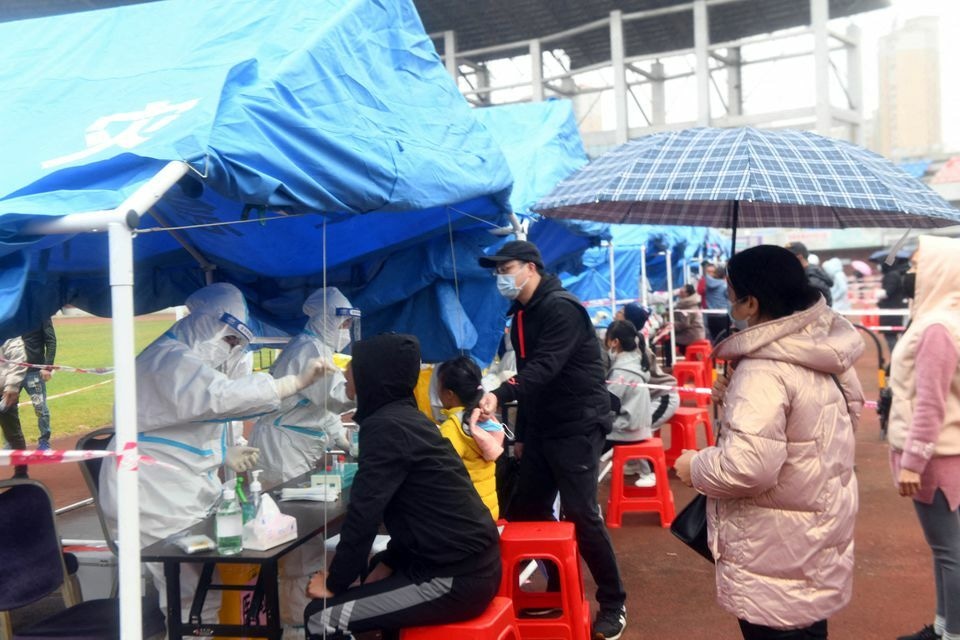 People line up in the rain at a nucleic acid testing site following cases of the coronavirus in Dongxing, a border city with Vietnam, in Guangxi Zhuang Autonomous Region, China, December 27. — Reuters