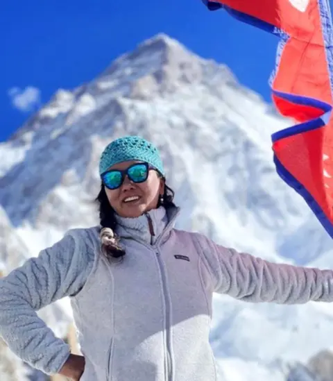 Netflix Lhakpa Sherpa smiling on a mountain with a flag