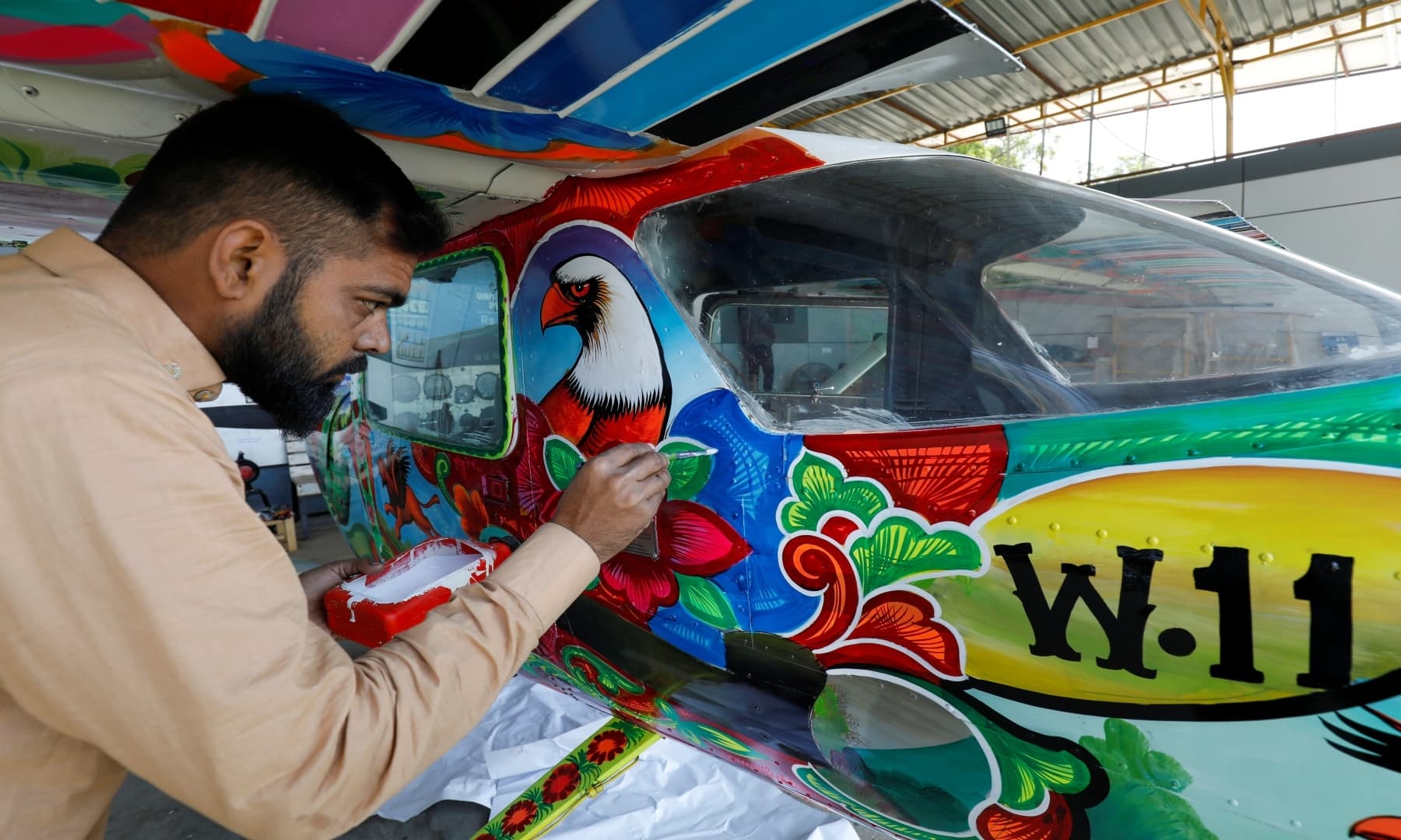 A man paints Pakistani truck art on a two-seater Cessna aircraft at general aviation area at Jinnah International Airport, Dec 30, 2020. — Reuters