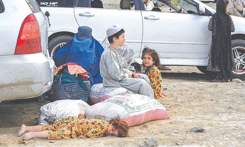 CHAMAN: A girl sleeps on the ground as her family members, along with other people, wait for the reopening of the border crossing point with Afghanistan on Friday. Across the border in Afghan town of Spin Boldak, fighting raged between Afghan forces and Taliban to retake the key border crossing point with Pakistan. (Right) Paramedics at a hospital in Chaman attend to the men injured in the fighting.—AFP
