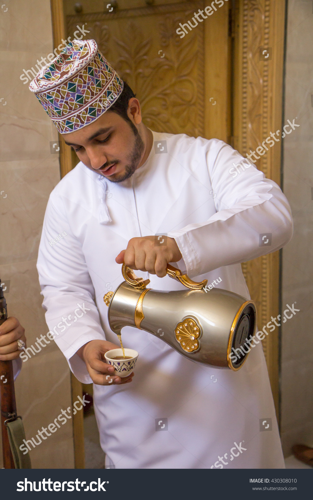 stock-photo-omani-man-in-traditional-clothing-serving-arabic-coffee-may-430308010.jpg