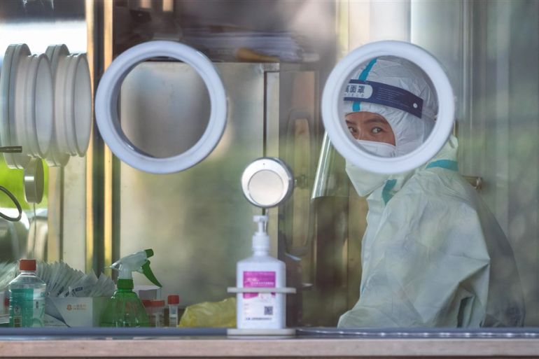 A Chinese medical worker sits in a COVID-19 testing booth at the Disney Resort in Shanghai, China, in November 2022