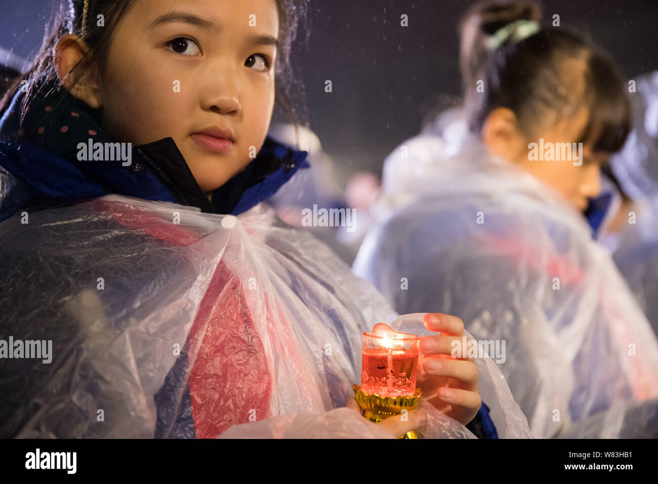 young-girls-hold-candles-in-the-rain-during-a-candlelight-vigil-to-mourn-the-victims-of-the-nanjing-massacre-at-the-memorial-hall-of-the-victims-in-na-W83HB1.jpg