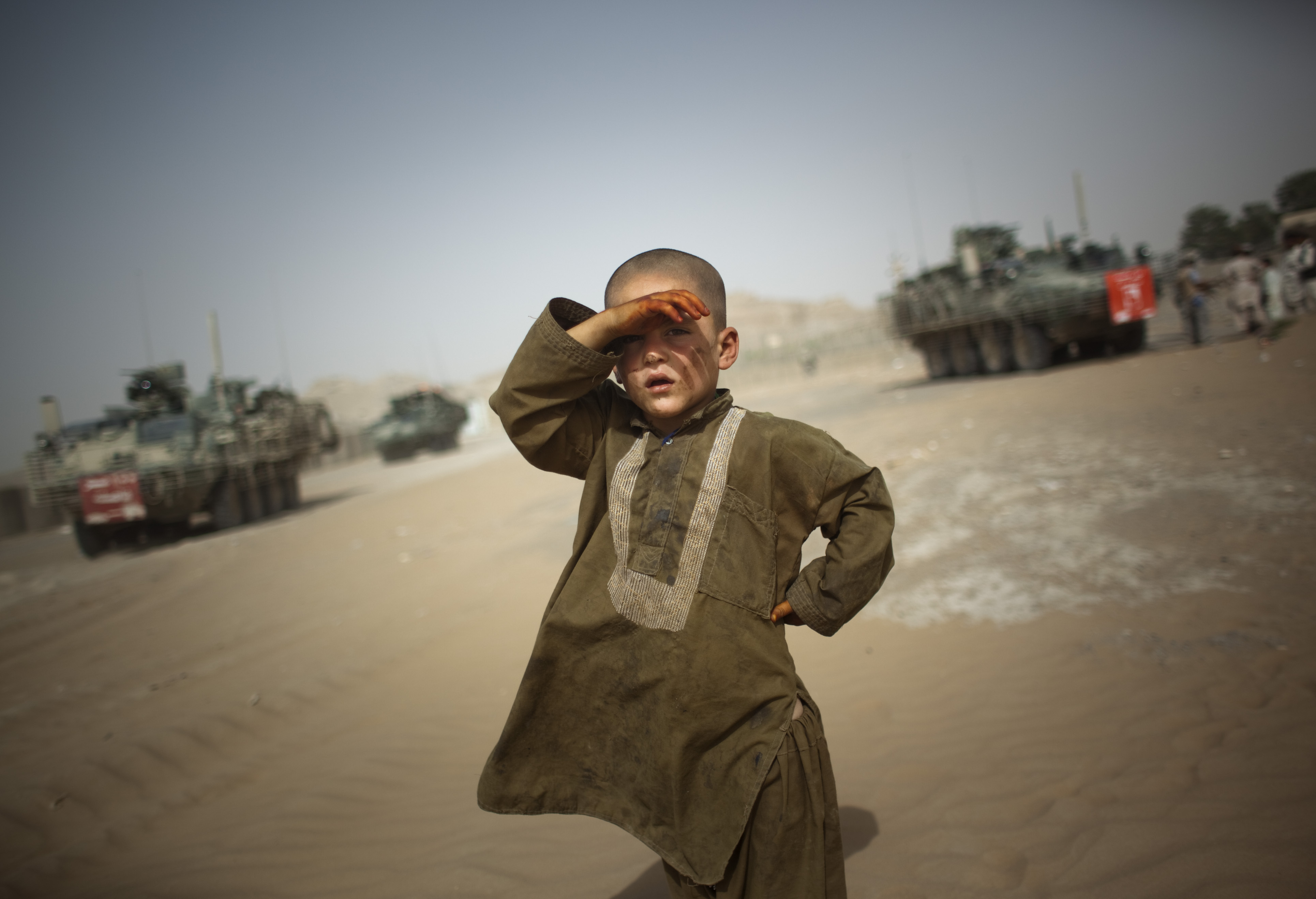 A child looks on as military vehicles drive past his Afghan village in 2009