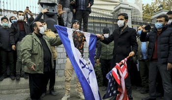 Protesters burn the U.S. and Israeli flags during a demonstration against the killing of Mohsen Fakhrizadeh, Iran's top nuclear scientist, in Tehran, Iran, in 2020.