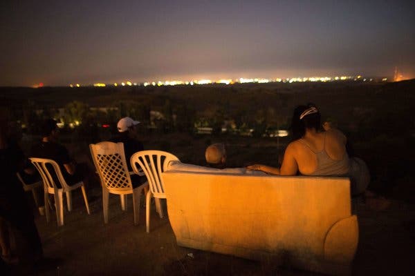 Israelis watched the bombing of Gaza on Saturday night from a couch dragged to a hill overlooking the Palestinian territory.