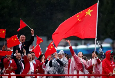  Steph Chambers/Getty Images Flagbearers Yu Feng of China and Long Ma of China, wave their flag on the team boat along the River Seine