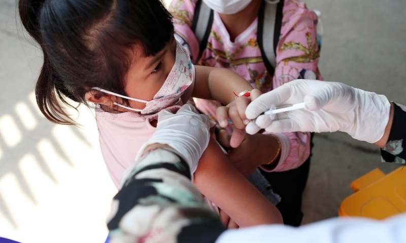 A young girl held by her mother pushes a shaft of a needle as she receives a first dose of Sinovac's Covie-19 vaccine at a health centre outside Phnom Penh, Cambodia on Feb 23. — AP