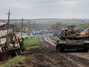 A Ukrainian tank drives next to a destroyed Russian vehicle, marked with the Z symbol, in the village of Husarivka on April 14.