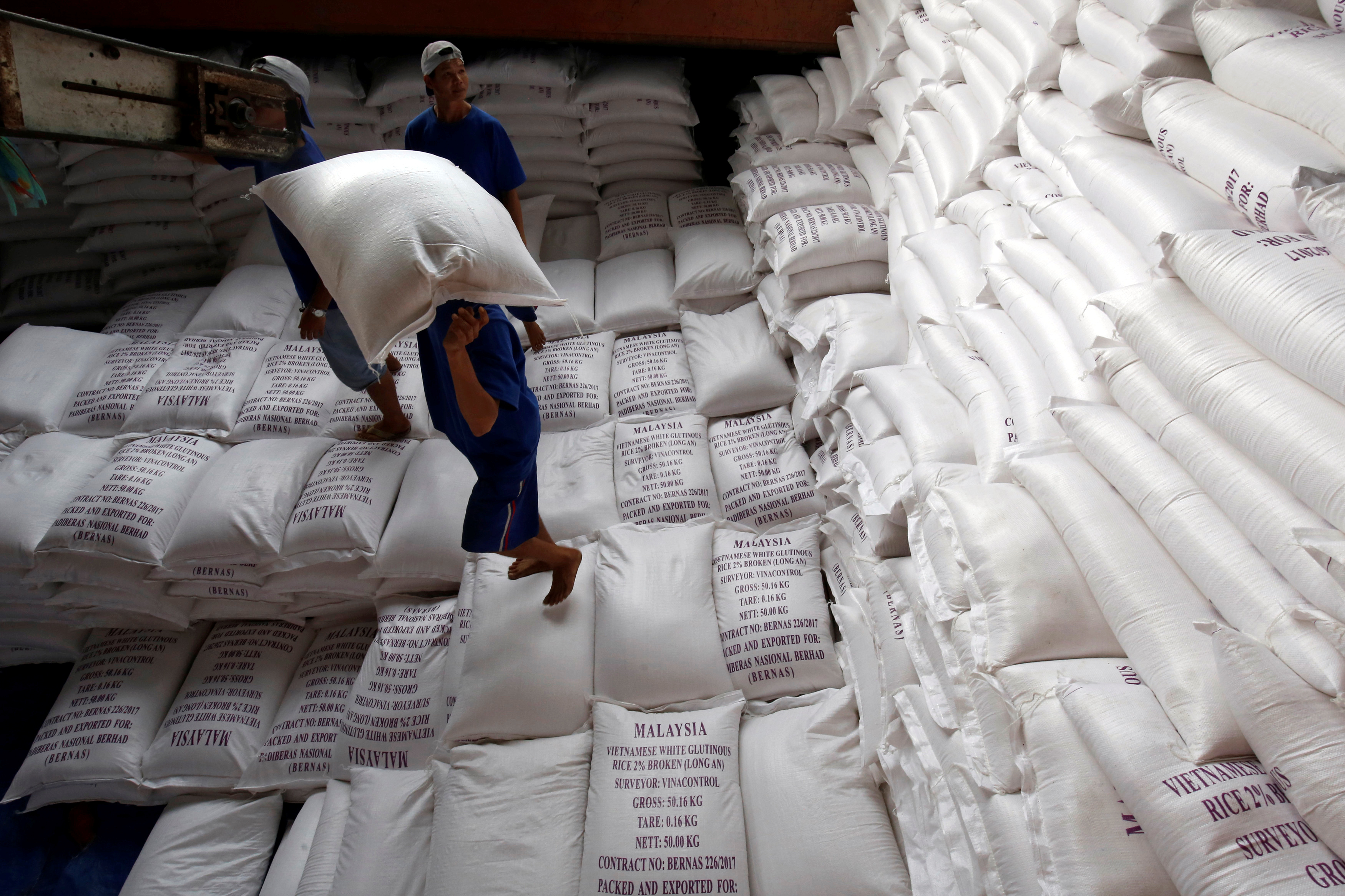 Men load rice bags to a ship for export at a rice processing factory in Vietnam's southern Mekong delta