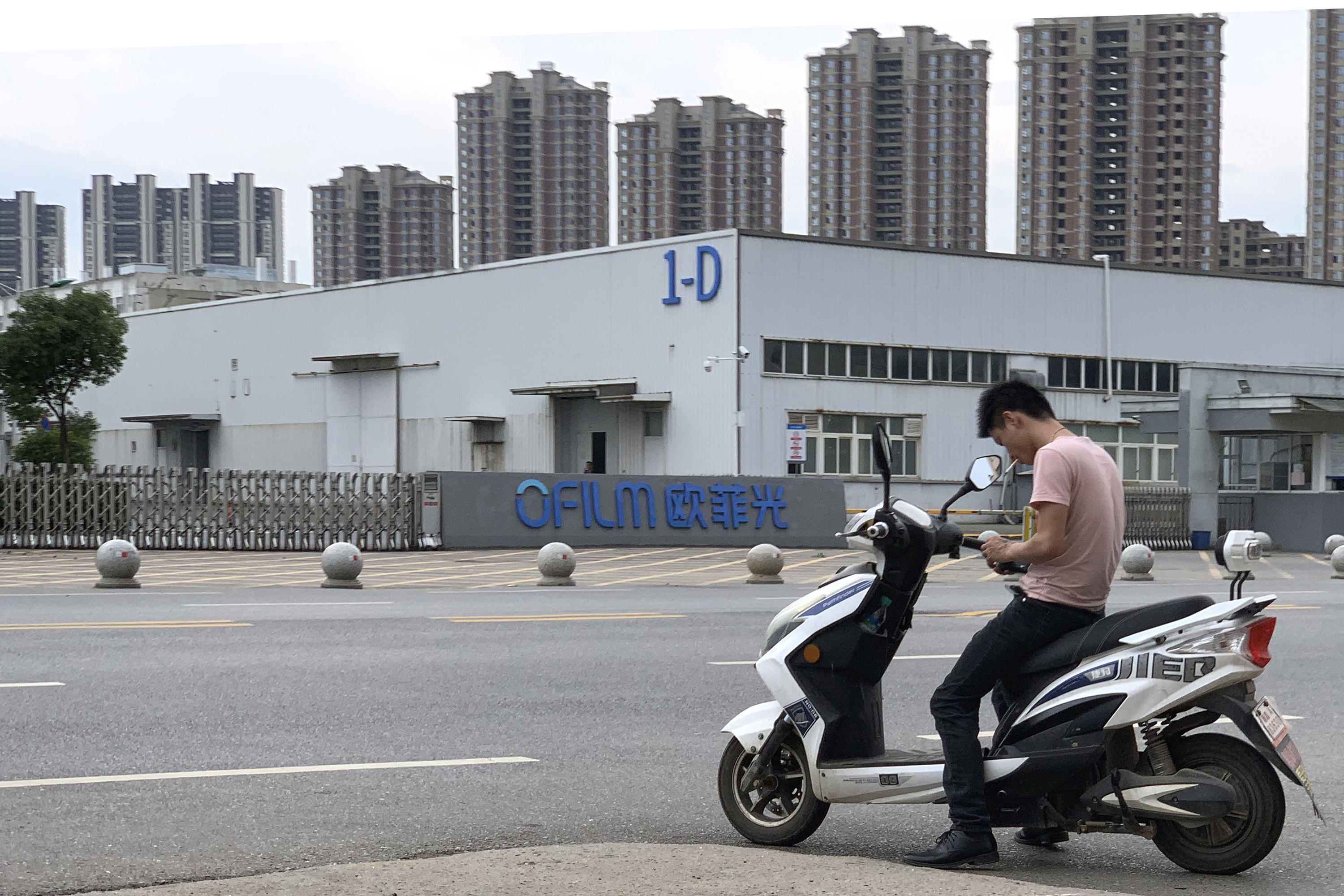 A local stops for a smoke near the entrance to an OFILM factory in Nanchang