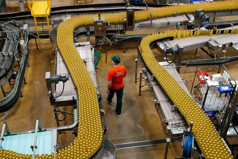 A worker walks between the production line at a bottling factory in Kegworth, UK.