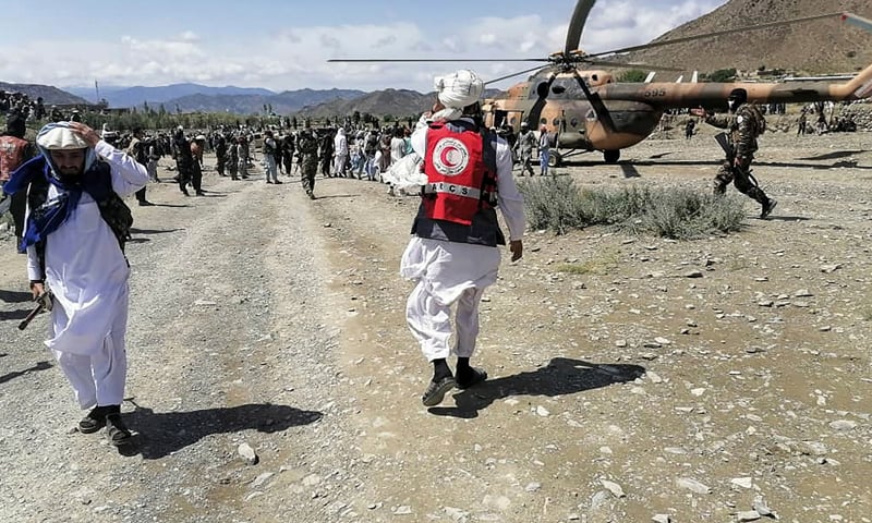 This photograph taken on June 22, 2022 and received as a courtesy of the Afghan government-run Bakhtar News Agency shows soldiers and Afghan Red Crescent Society officials near a helicopter at an earthquake hit area in Afghanistan's Gayan district, Paktika province. — AFP