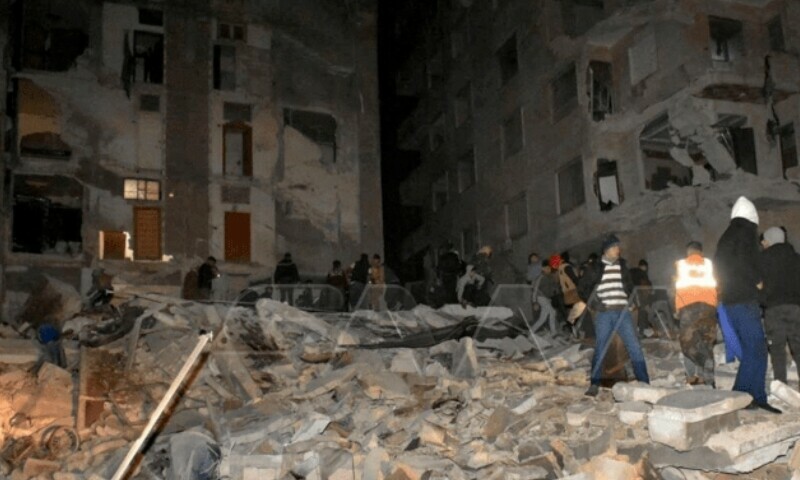 <p>People gather at the site of a collapsed building, following an earthquake in Hama, Syria on Feb 6. — Reuters</p>