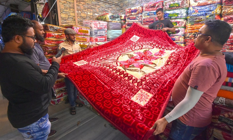 Salesmen show a Chinese blanket for customers at a market in Dhaka, Bangladesh, on Nov. 23, 2022.(Photo: Xinhua)