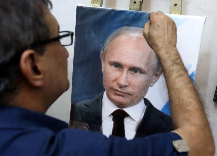 Iraqi artist Mohammed Karim Nihaya touches up a painting of Russian President Vladimir Putin in his studio in the Karada district of Baghdad on October 7, 2015 (AFP Photo/Sabah Arar)