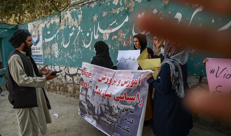 A member of the Taliban speaks with women protesters as another tries to block the view of the camera with his hand during a demonstration held outside a school in Kabul on Thursday. — AFP