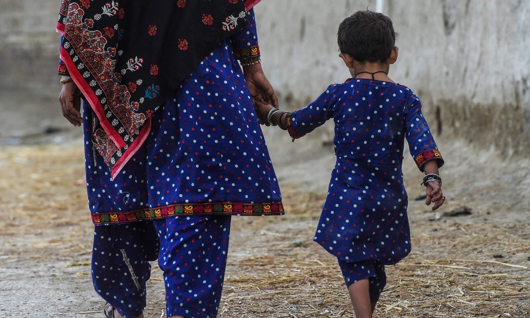 In this picture taken on March 25, Hakima Shar and her daughter, who are both HIV positive, walk outside their home in Subhani Shar village. —  AFP